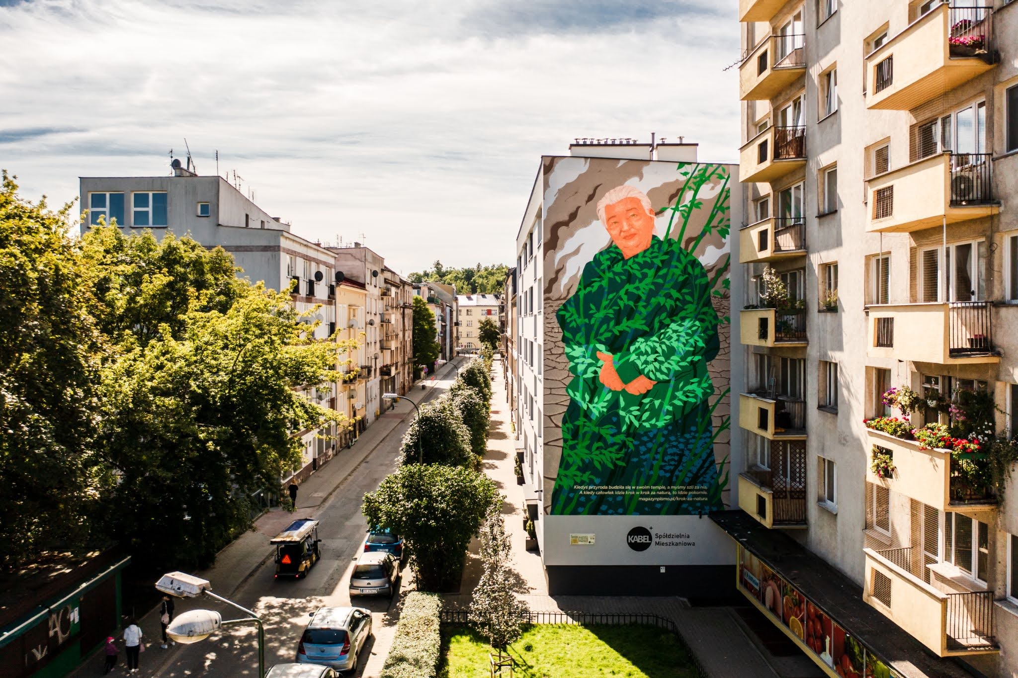 A beautiful building-sized mural of a local woman painted in green